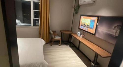 a small room with a bed and a television at JTOUR Inn Wuhan Textile University in Wuhan
