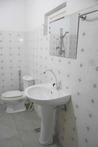 a white bathroom with a sink and a toilet at Grand Breeze Hotel 