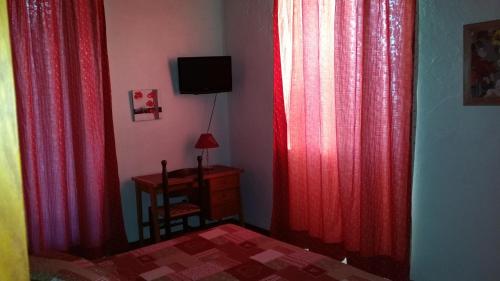 a bedroom with red curtains and a bed and a desk at HOTEL Le TOURISME in Passy