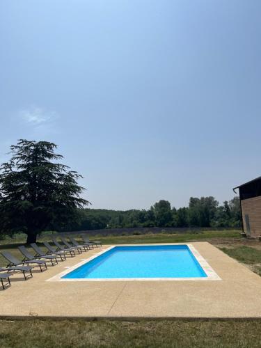 - une piscine avec des chaises et un arbre dans l'établissement Gite le Sagnac 10 personnes, à Sauzet