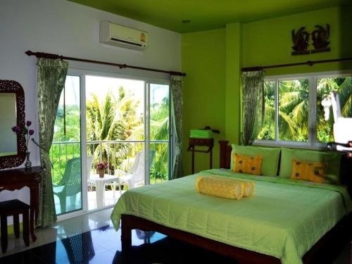 ein grünes Schlafzimmer mit einem Bett und einem großen Fenster in der Unterkunft Sairougn Seaview Hotel in Ban Ko Kwang