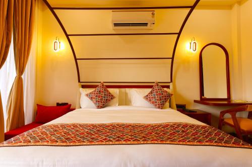 a bedroom with a large white bed with red pillows at Chitralekha Boutique Resort in Rājpur