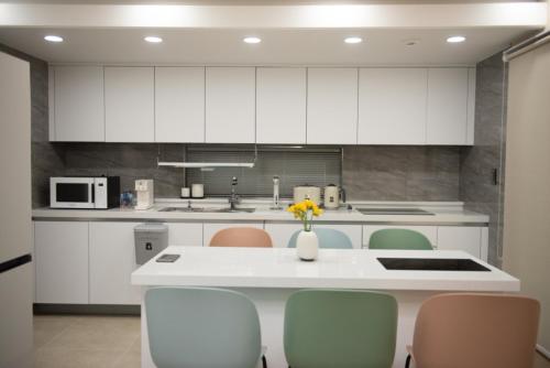 a kitchen with white cabinets and a table and chairs at Pool Story 6 in Jeju