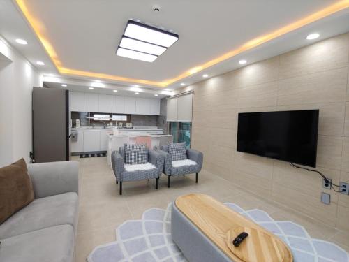 a living room with a couch and a flat screen tv at Pool Story 6 in Jeju