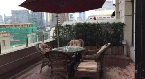 a table and chairs on a balcony with an umbrella at Jinjiang Metropolo Hotel Classiq Shanghai Off Bund in Shanghai