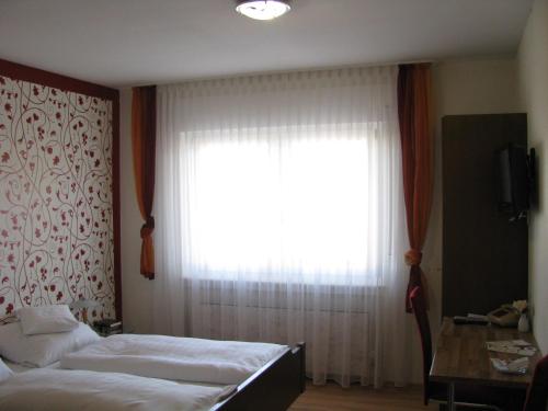 a bedroom with two beds and a large window at Hotel Bürgerstube in Muggensturm