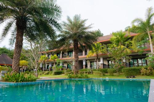 a resort with a swimming pool and palm trees at Poochommhok Resort in Sangkhla Buri