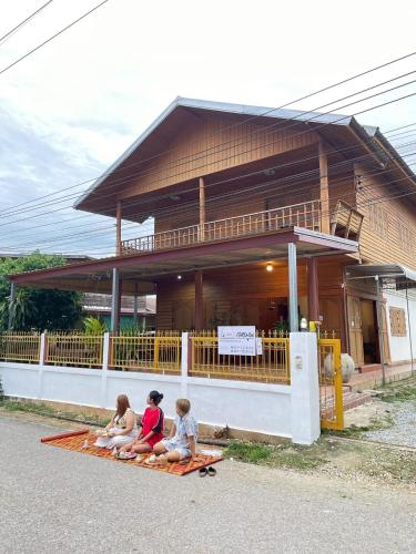 three children sitting on a blanket in front of a building at Le Moon Hotel in Chiang Khan