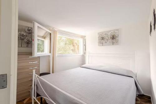 a white bedroom with a bed and a window at villa Antony in San Michele Salentino