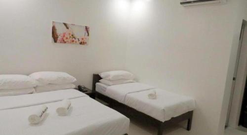 two beds in a room with white walls at Fiesole Residence Inn in Dumaguete