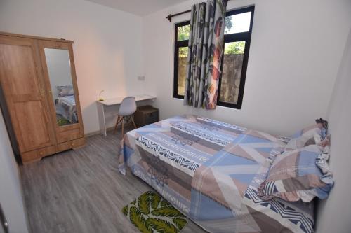 a bedroom with a bed and a table and a window at Maison LE GLAS in Curepipe