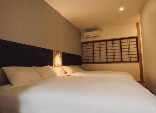 a bedroom with a large white bed with a window at 東福寺2 都憶 in Kyoto