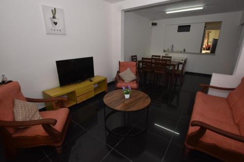a living room with chairs and a tv and a table at Maison LE GLAS in Curepipe