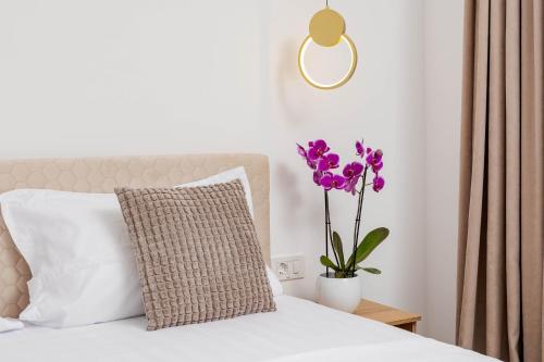 a bed with a pillow and a vase with purple flowers at Hotel Boutique Tunari in Tunari