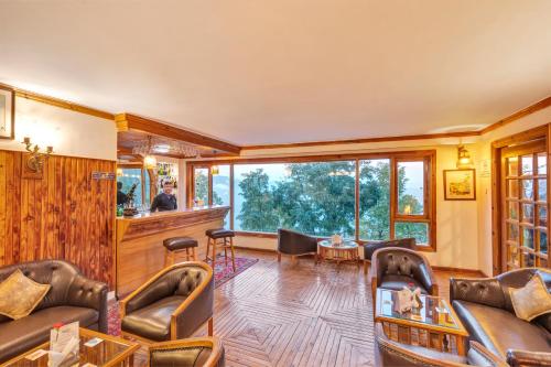 a living room with leather furniture and a large window at Club Mahindra Mashobra in Mashobra