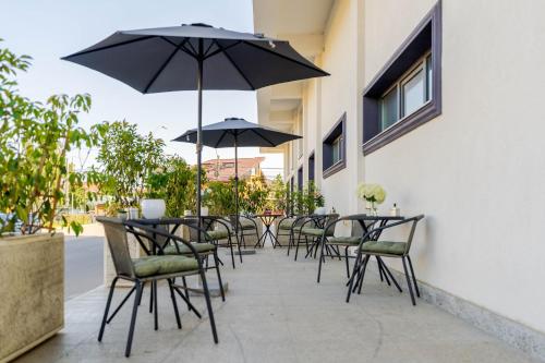 a patio with tables and chairs with an umbrella at Hotel Boutique Tunari in Tunari