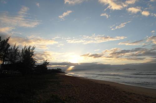 a sunset on a beach with the ocean at Hotel Bellatrix in Macaé