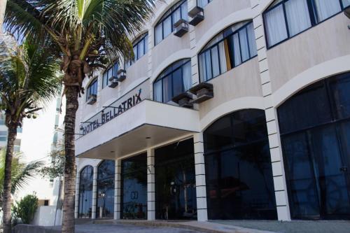 a building with palm trees in front of it at Hotel Bellatrix in Macaé