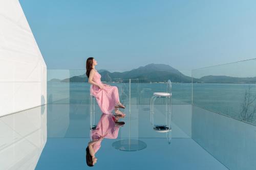 a woman in a pink dress is standing on a glass floor at private soup holiday villa by the sea in Dapeng