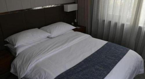 a bed with white sheets and pillows next to a window at Beijing Friendship Hotel Jing Bin Building in Beijing