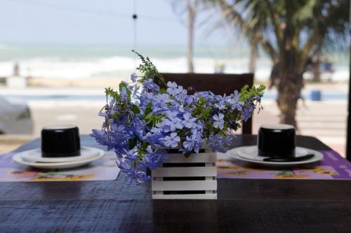 a table with a vase of purple flowers and two hats at Hotel Bellatrix in Macaé