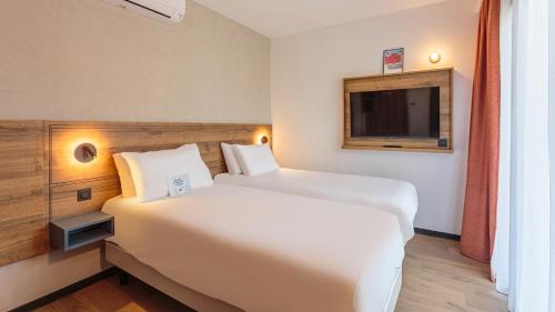 a hotel room with two beds and a tv at KYRIAD DAX - Saint Paul lès Dax in Saint-Paul-lès-Dax