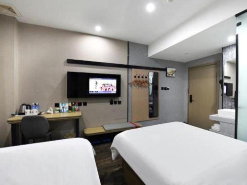 a room with a bed and a desk and a tv at Thank Inn Hotel He'nan Xinxiang Changyuan Bo'ai Road in Changyuan
