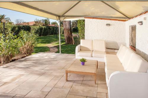 a patio with white furniture and a large umbrella at Fattoria Maremmana in Marina di Grosseto