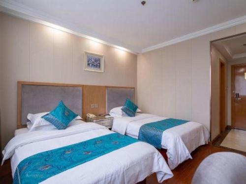 a hotel room with two beds with blue pillows at GreenTree Inn Wuxi Xinwu District Meicun Town Taibo Avenue in Wuxi