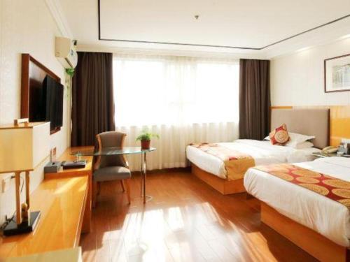 a hotel room with two beds and a desk at GreenTree Inn Wuxi Xinwu District Meicun Town Taibo Avenue in Wuxi