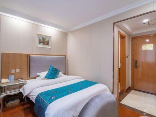 a bedroom with a large bed with blue pillows at GreenTree Inn Wuxi Xinwu District Meicun Town Taibo Avenue in Wuxi