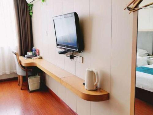 a tv on a wall in a hotel room at GreenTree Inn Wuxi Xinwu District Meicun Town Taibo Avenue in Wuxi