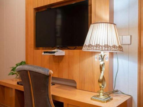 a lamp sitting on a desk next to a television at GreenTree Inn Wuxi Xinwu District Meicun Town Taibo Avenue in Wuxi