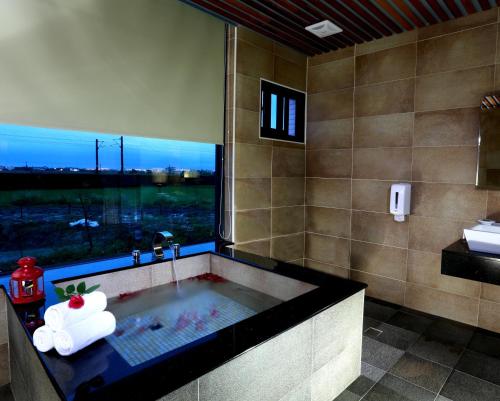 a bathroom with a bath tub with a window at Artisan Hostel in Toucheng