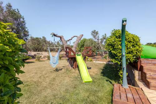 a playground with a slide and a swing at villa Antony in San Michele Salentino