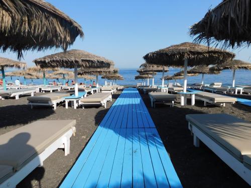 a row of benches and umbrellas on a beach at Perissa South Beach Suites in Perissa