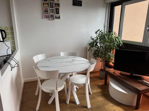 une table blanche et des chaises dans une pièce avec une télévision dans l'établissement Appartement lumineux 46m2 20e, à Paris