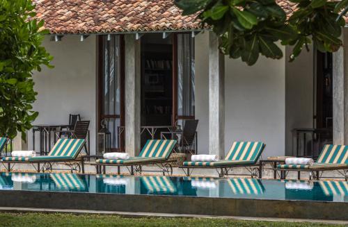 a group of chairs sitting next to a swimming pool at The Frangipani Tree by Edwards Collection in Unawatuna