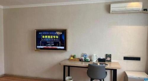 a room with a desk with a television on the wall at GreenTree Inn Xuzhou High Speed Railway Station Express Hotel in Xuzhou