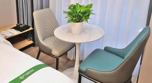 a small table with two chairs and a plant on it at GreenTree Inn Suzhou Shihu Suli Road Express Hotel in Suzhou