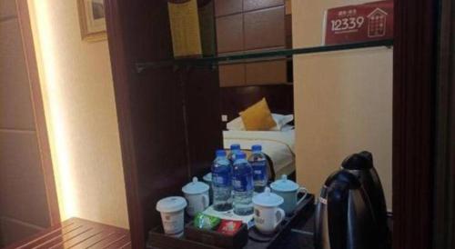 a shelf with bottles of water and cups in a room at Tianrun International Hotel in Dunhuang
