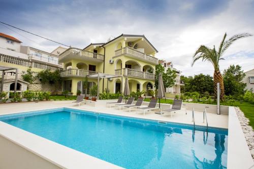 ein großes Haus mit Pool davor in der Unterkunft Apartments Bago in Trogir