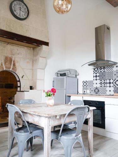 Una mesa y sillas en una cocina con un reloj. en Le Four à Chanvre, en Saint-Genest-dʼAmbière