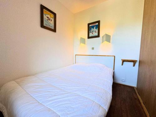 un lit dans une chambre avec deux tableaux au mur dans l'établissement Résidence Necou - Appartement 4 persons en bord de pistes MAE-5094, aux Menuires