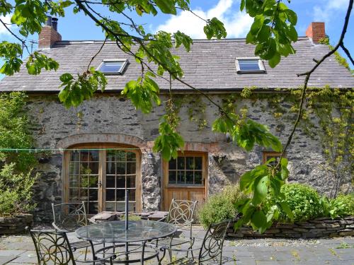 a stone house with a table and chairs in front of it at Hen Dy Goits in Llangadwaladr