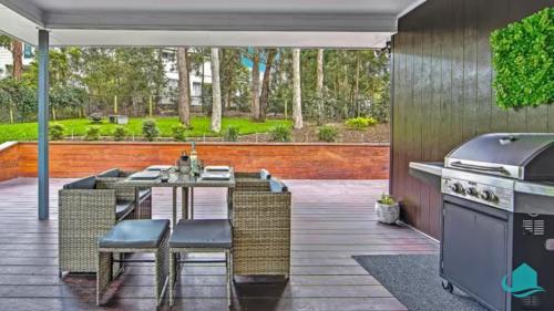 an outdoor kitchen with a table and chairs and a grill at Stay A While at Murrays Beach in Cams Wharf