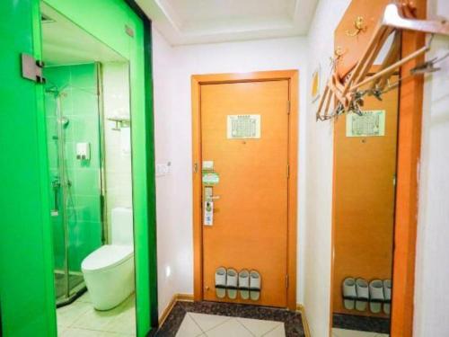 a bathroom with a toilet and a wooden door at Vatica HeFei Baishuiba BHG Hotel in Hefei