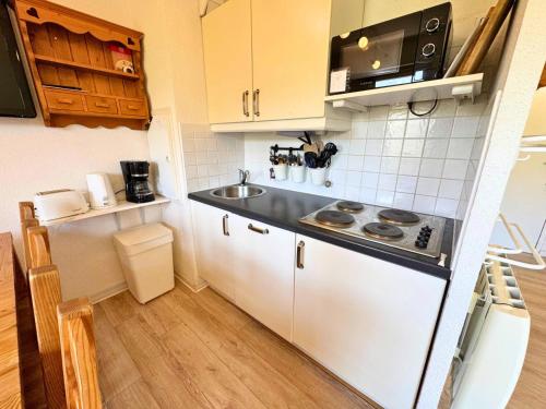 une petite cuisine avec un évier et une cuisinière dans l'établissement Résidence Necou - Grand duplex rénové pour 6 personnes MAE-3904, aux Menuires