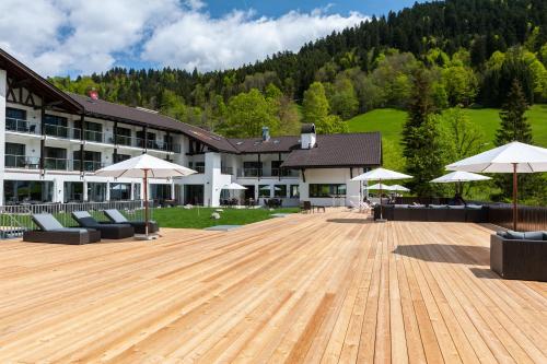 a large building with a wooden deck with umbrellas at Das Graseck - mountain hideaway & health care in Garmisch-Partenkirchen
