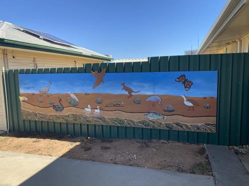 Una valla verde con un mural de animales. en Bedourie Tourist Park, 